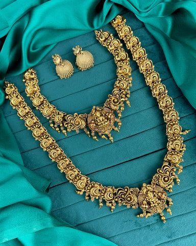 Ornate gold necklace and earrings on a teal fabric background