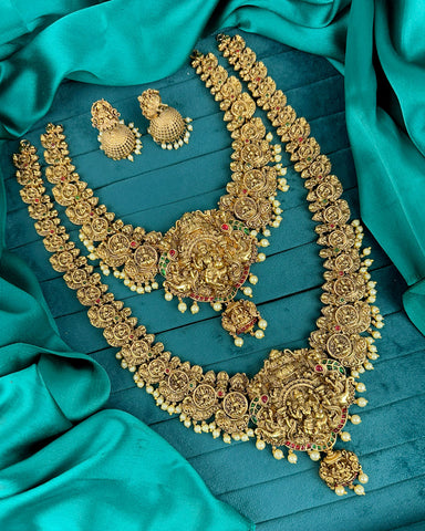 Gold necklace and earrings set on a teal fabric background