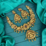 Ornate gold necklace and earrings on a teal fabric background