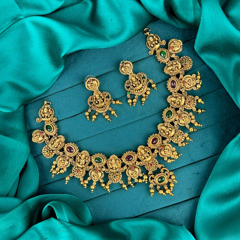 Gold necklace and earrings on a teal fabric background