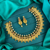 Gold necklace and earrings set on a teal fabric background