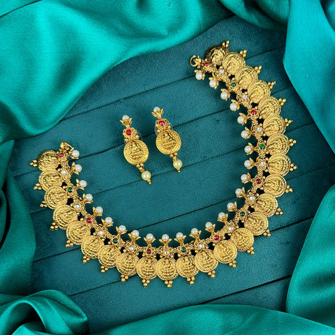 Gold necklace and earrings set on a teal fabric background