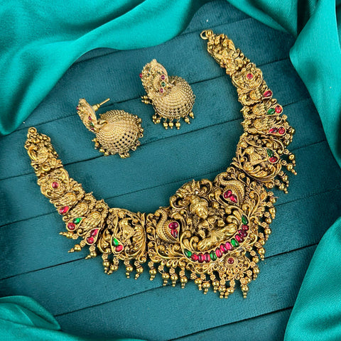 Gold necklace and earrings on a teal fabric background