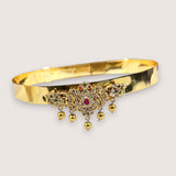Gold bracelet with decorative elements on a light gray background