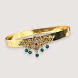 Gold bracelet with gemstone decorations on a light gray background