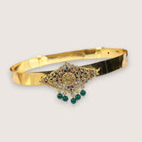 Gold bracelet with gemstones on a light gray background