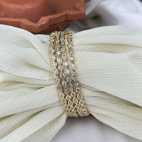 Gold bracelet with clear stones on a white flower