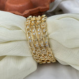 Gold bracelets with diamond accents on a white fabric background