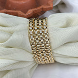 Gold bracelet with diamond accents on a white fabric background