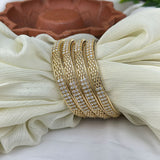 Gold bangles with crystals on a white fabric background