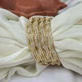 Gold bangles with intricate designs on a white fabric background