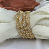 Gold bracelets with diamond-like stones on a white fabric background