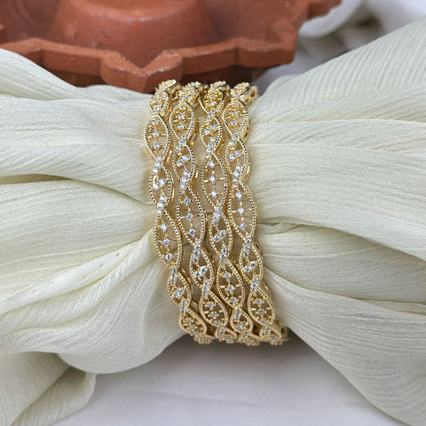 Gold bracelet with intricate design on a white fabric background