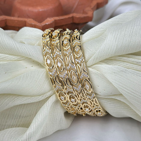 Gold bracelet with intricate design on a white fabric background