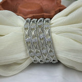 Silver bracelet with leaf pattern on a white fabric background