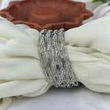 Silver bracelet with intricate design on a white fabric background