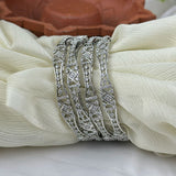 Three silver rings with diamond-like stones on a white fabric background