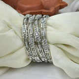 Set of silver bracelets with intricate designs on a white fabric background