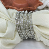 Silver bangles with diamond-like stones on a white fabric background