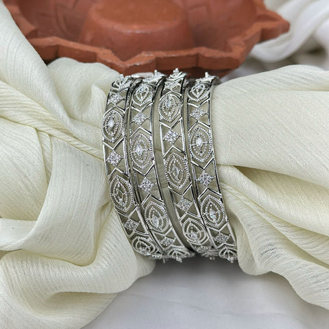 Silver bangles with diamond-like stones on a white fabric background