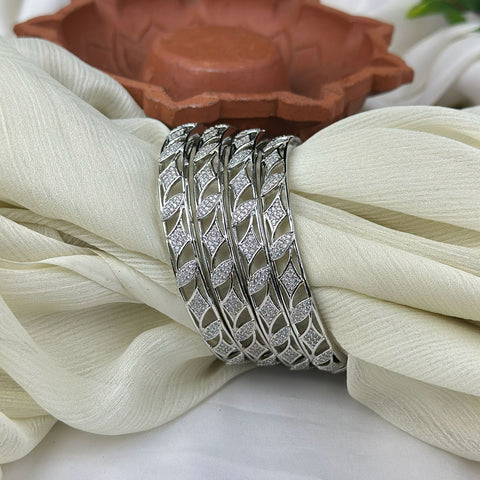 Set of silver bangles on a white fabric with a terracotta dish in the background