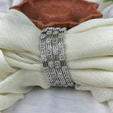 Silver bracelet with gemstones on a white fabric background