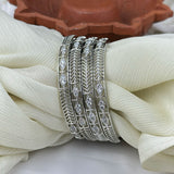 Set of silver bangles with diamond-like stones on a white fabric background