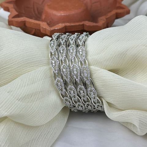Silver bracelets on a white fabric with a terracotta dish in the background