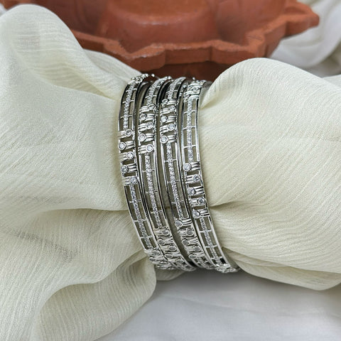 Set of silver bangles on a white fabric background