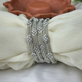 Silver bracelet with intricate design on a white fabric background
