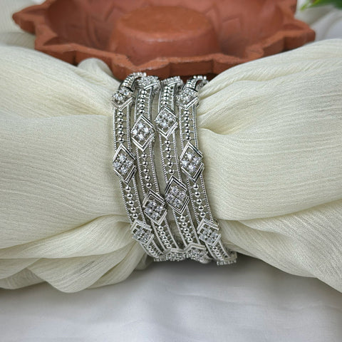 Silver bracelet with intricate design on a white fabric background