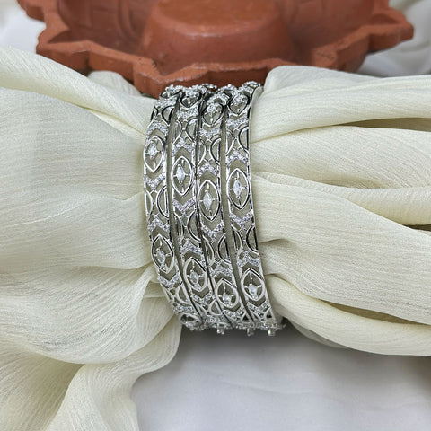 Three silver rings with intricate designs on a white fabric background