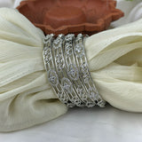 Set of silver bangles on a white fabric background