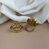 Gold earrings with intricate designs on a beige surface with white fabric in the background