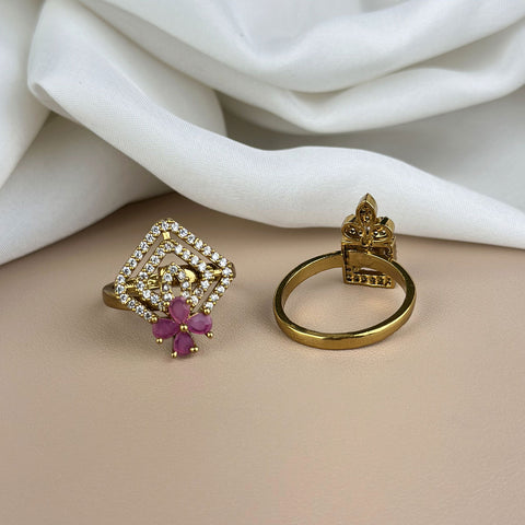 Two gold rings with decorative designs on a beige surface with white fabric in the background