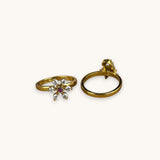Gold ring with a snowflake design and gemstone on a white background