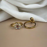Gold ring with gemstones on a beige surface with white fabric in the background