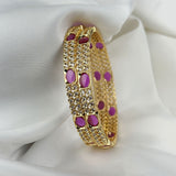 Gold bracelet with purple stones on a white fabric background