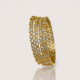 Gold bracelet with diamond-like stones on a light beige background