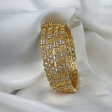 Gold bracelet with diamond-like stones on a white fabric background