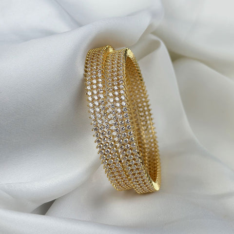 Gold bracelet with clear stones on a white fabric background