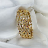 Set of gold bangles with gemstones on a white fabric background