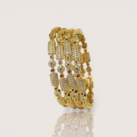 Set of gold bracelets with gemstones on a light gray background