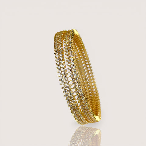 Gold bracelet with clear stones on a light gray background