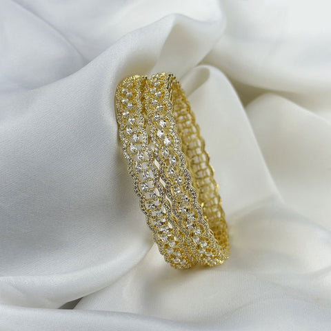 Gold bracelet with clear stones on a white fabric background