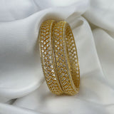 Gold bracelet with intricate design on a white fabric background