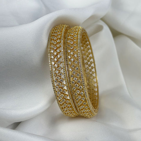 Gold bracelet with intricate design on a white fabric background