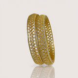 Gold bangles with diamond-like stones on a light beige background