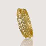 Gold bangles with embedded stones on a light gray background