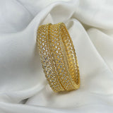 Gold bracelet with clear stones on a white fabric background